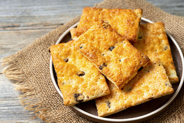Puff dessert with raisins in a plate on a wooden light gray culinary background. Delicious homemade sweet pastries	