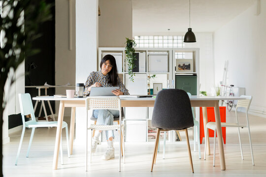 Female entrepreneur with graphic tablet sitting on desk at office
