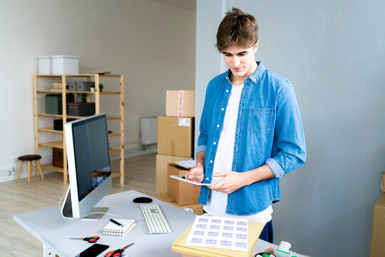 Male professional with digital tablet examining QR codes at desk in office