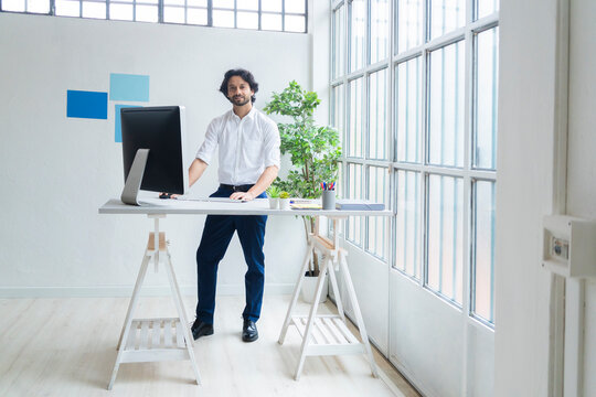 Young male entrepreneur standing by desk in office