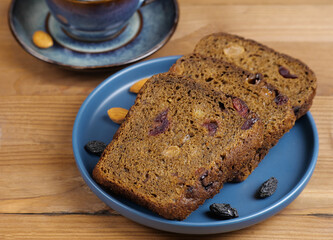 Whole-grain rye bread close-up on a blue plate, with raisins, nuts.