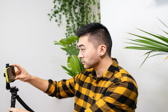 Male professional adjusting smart phone on tripod in office