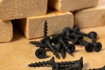 black small screws for wood on a wooden background
