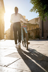 young woman seen from behind push a bike seen from behind