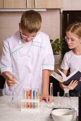 a boy and a girl are doing a chemical experiment at home. The white boy is studying online. Home laboratory. Experiments in the kitchen at home. The children are doing their homework.