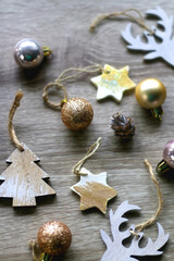 Various wooden Christmas ornaments, golden baubles and pine cones on wooden background. Selective focus.