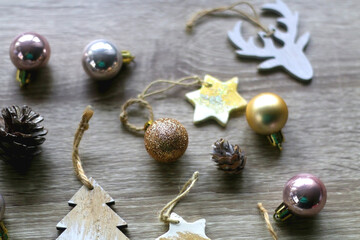 Obraz na płótnie Canvas Various wooden Christmas ornaments, golden baubles and pine cones on wooden background. Selective focus.