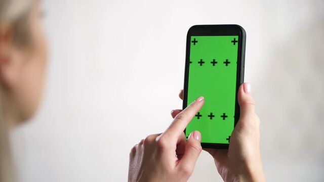 Close up shots of green screen on iphone. Lady holding in hands mobile phone device with moving interactive motion tracking points. Touching, tapping smartphone surface with fingers, sliding, swiping.