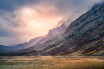 Glencoe mountain range at sunset with sun beams penetrating the clouds in Scotland © Studio-FI