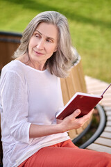 Meditative woman with book sitting on bench