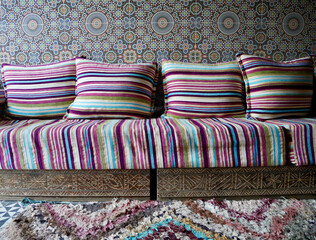Close up of traditional colorful Moroccan seating with ornate mosaic and handmade carpets at a Berber home. High Atlas Mountains, Morocco.