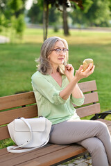 Woman looking in mirror sitting on bench