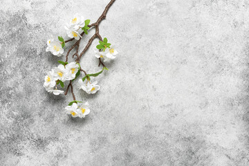 Blooming cherry branch (artificial) on a gray grunge background. Beautiful spring background. Top view, flat lay, copy space