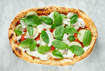 Roman pizza with spinach, zucchini slices, stracciatella cheese and tomatoes on marble background.....