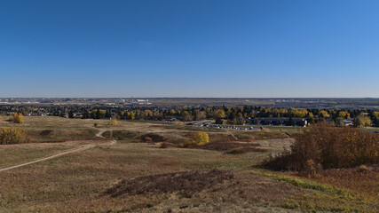 Beautiful panoramic view over Nose Hill Park in the north of Calgary, Alberta, Canada in autumn season with colorful meadows, parking and airport.