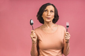 Photo of cheerful aged mature senior woman with spoon and fork eating delicious healthy meal...