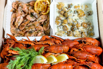 large box with crayfish shrimps and raps in white sauce
