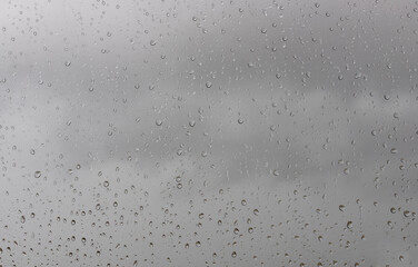 Rain drops on window glasses surface with cloudy background . Natural Pattern of raindrops isolated on cloudy background.