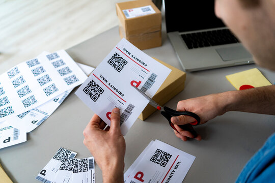 Businessman cutting QR label with scissor at desk