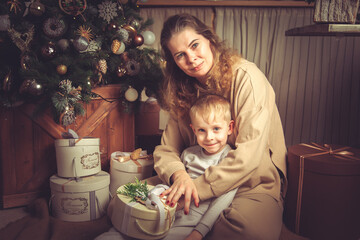 Mom and son are sitting near the Christmas tree. - Powered by Adobe