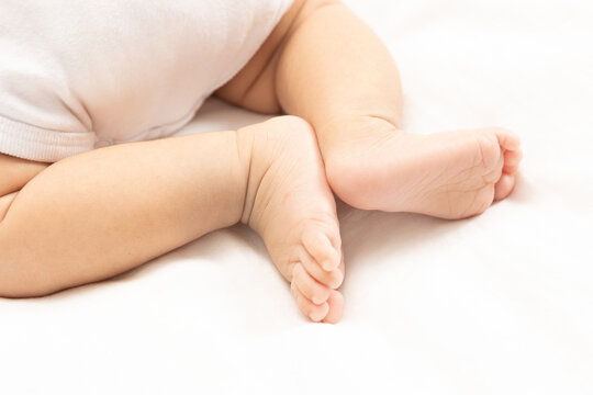 close up asian woman small baby infant feet while sleeping on soft bed covered with white cloth.
