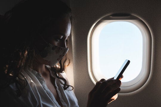 Female professional using smart phone in airplane during pandemic