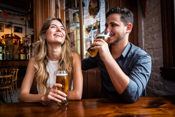 man drinking beer in bar. woman laughing
