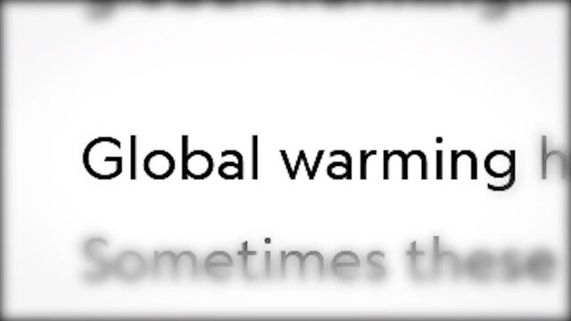 Threat of global warming in the text of electronic print media. Fast-paced macro text in the center of the screen. Breaking news concept about environmental problem.