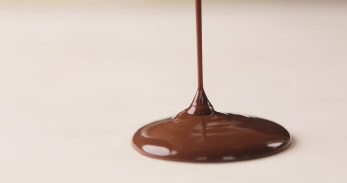 Melted chocolate syrup is pouring on a white background. Isolated. Making homemade cookies. Home confectionery.
