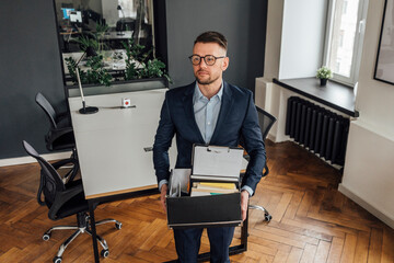 Thoughtful male entrepreneur holding belongings while standing at office