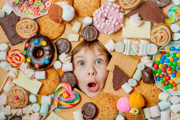 Fototapeta na wymiar Little girl lying under plenty of sweet foods