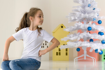 Girl Posing Next to White Christmas Tree Holding Bauble
