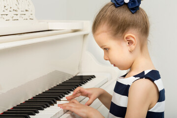 Lovely little girl playing grand piano in studio