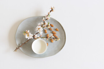 Flowering branch of almond and cup of almond milk on a white background.Healthy eating concept.Copy space.