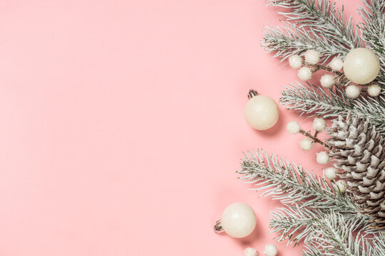 Christmas decorations at pink background. Fir tree and white christmas decorations. Flat lay with copy space.