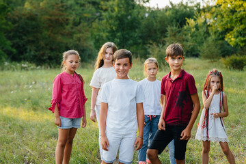 Fototapeta premium A group of happy children run and play in the Park during sunset. Summer children's camp