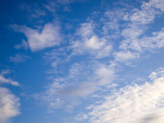 Obraz premium Bottom view of a bright blue sky with white and gray clouds. Sunny day. Abstract background.