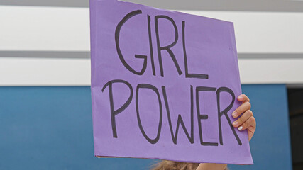 Detail of a girl's hand holding a sign with the slogan: girl power. 