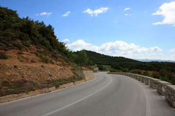 Asphalt road in the mountains. Beautiful nature around. Traveling by car on a bright, sunny day.