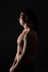 Naklejka premium side view of a man portrait of a low key man looking down on black background