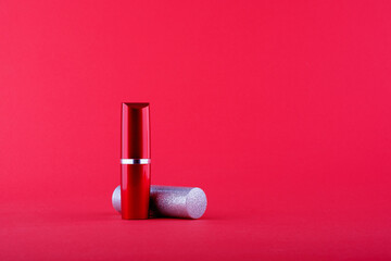 two bottles of lipstick grey lies red standing on a red background