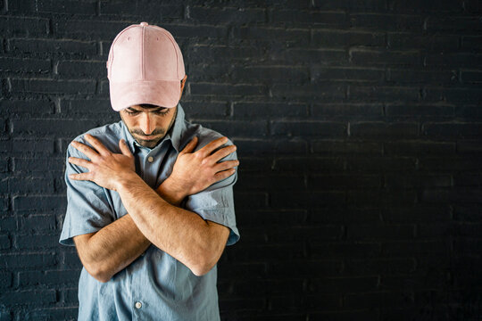 Worried man wearing cap standing in front of wall