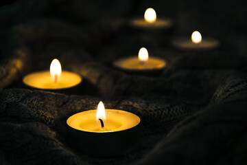 Burning candles and a warm knitted winter blanket