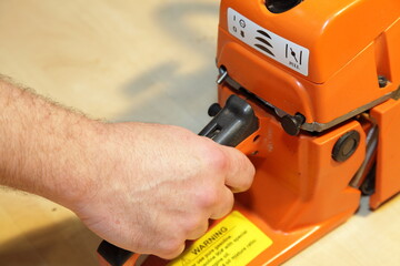 A man's hand holding the chainsaw handle with the throttle trigger of the closeup - forester tools equipment service