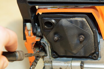 Exhaust pipe and silencer of a chainsaw on the background of a screwdriver in hand for cleaning the drive mechanism of the saw chain - woodcutting tools equipment check