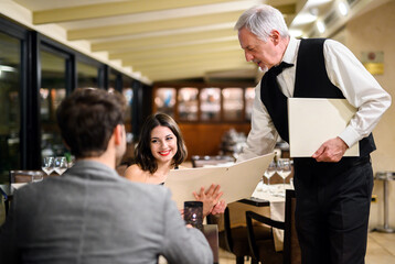 Waiter giving a menu to a couple in an elegant restaurant