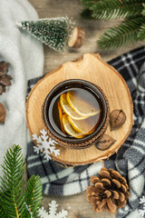 Obraz na płótnie Canvas Hot black tea and lemon with winter decor. Cozy sweater, fir tree branches, nuts, snowflakes