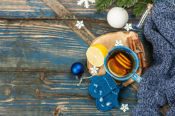Hot drink with crocheted funny mittens. Traditional winter decor, fir tree branches, snowflakes
