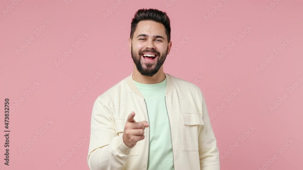 Wall mural Confident leader cheerful young bearded brunet man 20s wears white shirt point index finger camera on you showing thumb up like gesture isolated on plain pastel light pink background studio portrait