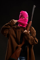 woman in glamorous pink mask shotgun posing black background